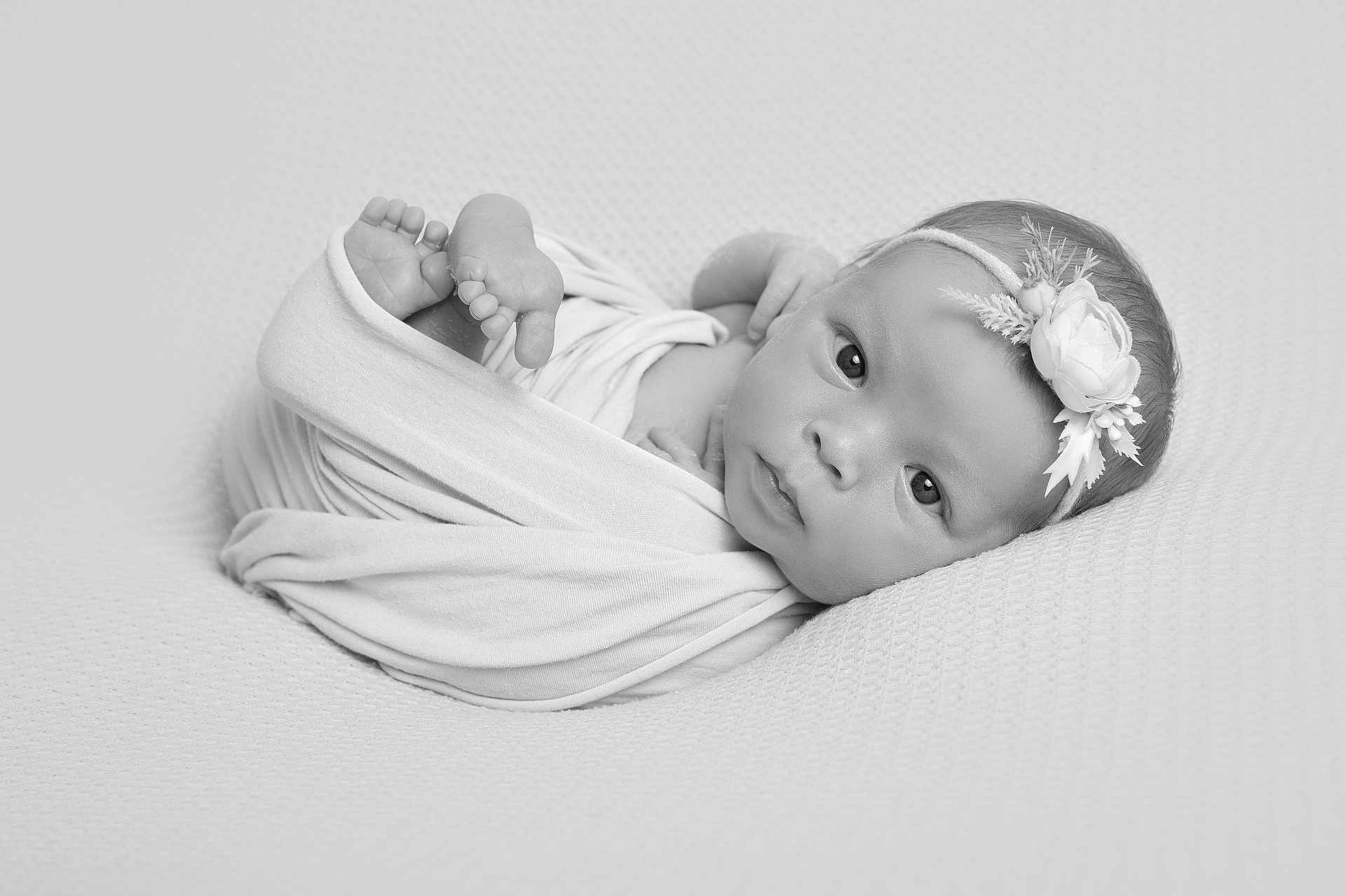 Naevia-J is registered to the contest to win money with this photo: newborn, baby, infant, swaddled, black_and_white, portrait, headband, flower, soft_texture, peaceful, resting, curious_gaze, wrapped, cute, small_feet, closeup, monochrome, baby_face, lying_down, blanket