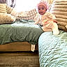baby, child, infant, crown, smiling, sitting, sofa, couch, quilt, blanket, cushion, living_room, indoors, window, curtains, wooden_floor, clothing, portrait, home, cozy