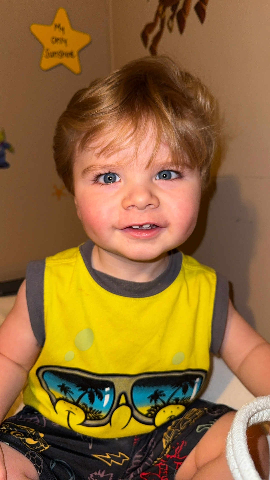 Ryder joined the competition — help win amazing prizes! toddler, child, smiling, yellow_shirt, blonde_hair, blue_eyes, indoor, sitting, tank_top, graphic_tshirt, cute, happy, face, person, shorts, playful, young_child, casual_clothing, portrait, closeup