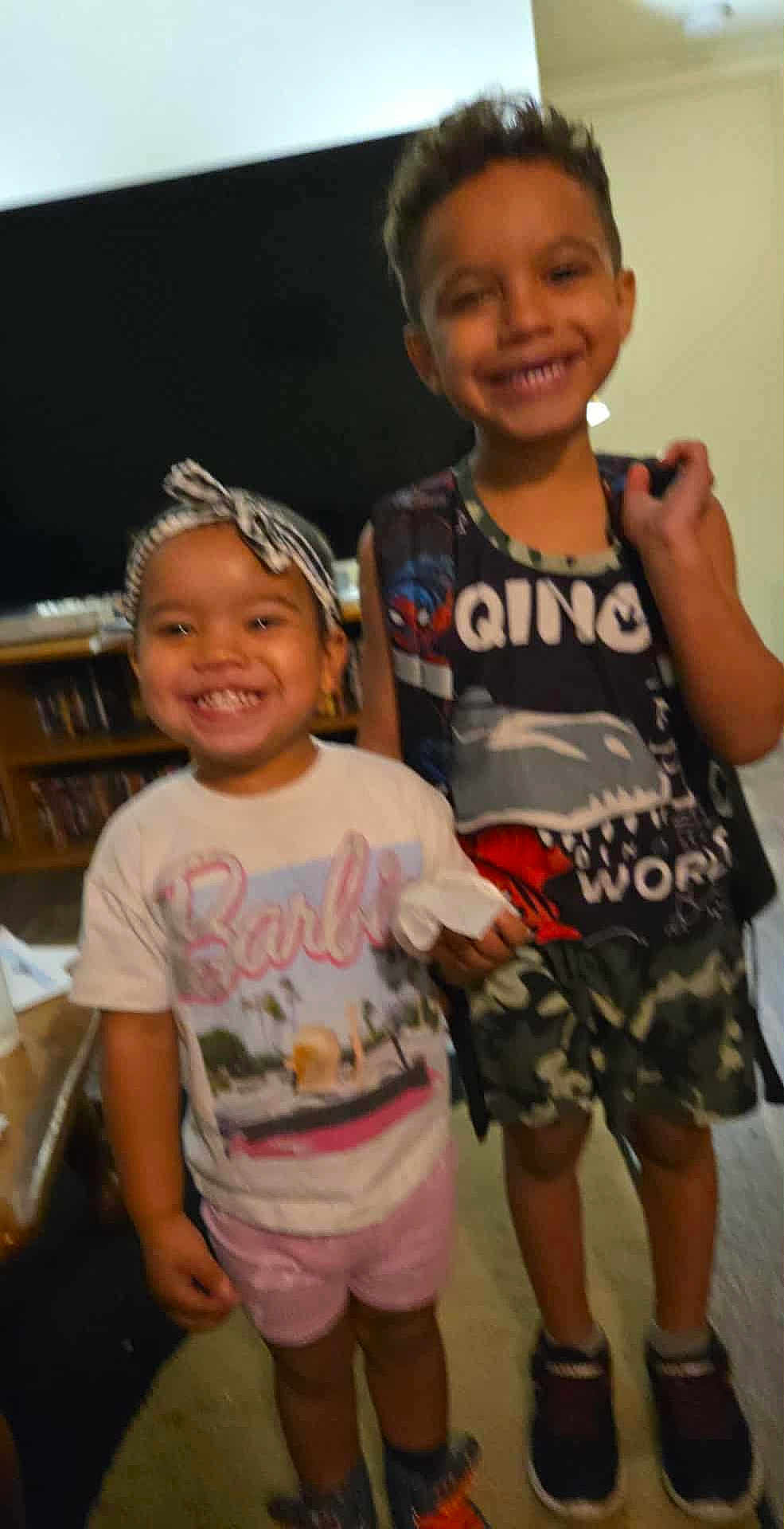 Hennessy joined the competition — help win amazing prizes! child, smiling, indoor, tshirt, shorts, headband, boy, girl, happy, standing, carpet, furniture, television, socks, shoes, person, camo, clothing, living_room, blur