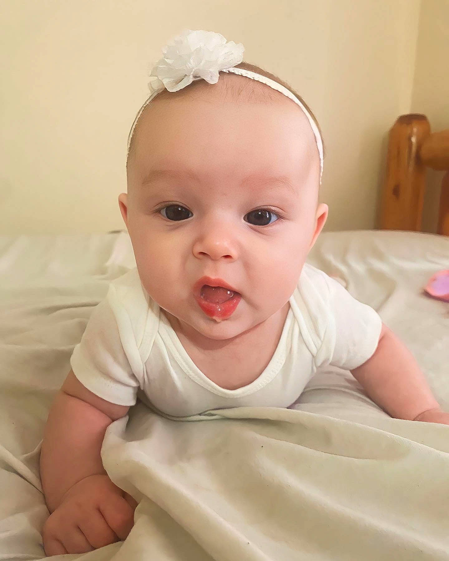 Alora is registered to the contest to win money with this photo: baby, baby_toddler_clothing, cheek, child, comfort, eyelash, finger, hair_accessory, happy, headband, headpiece, iris, linens, lip, neck, person, pink, skin, sleeve, smile