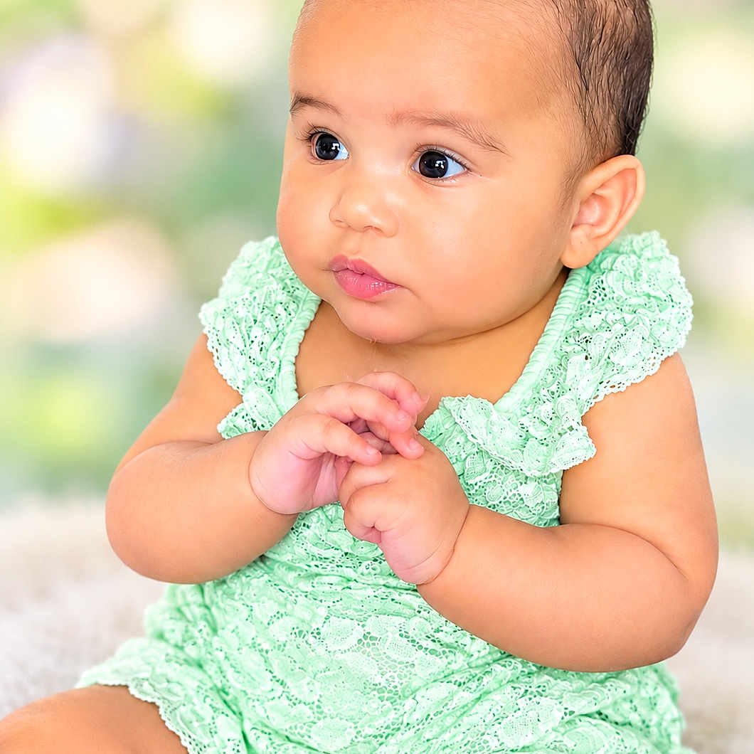 Kea'Laiah joined the competition — help win amazing prizes! baby, infant, child, portrait, sitting, mint_green_outfit, lace, dress, hair_buns, clasped_hands, wide_eyes, round_cheeks, looking_sideways, smiling, indoor, soft_lighting, bokeh, close_up, photography, cute