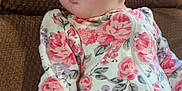 Copelynn is registered to the contest to win money with this photo: baby, infant, child, floral_clothing, onesie, couch, brown, texture, curious_expression, puckered_lips, hand, portrait, indoors, young_child, cute, soft_lighting, comfortable, sitting, face, skin