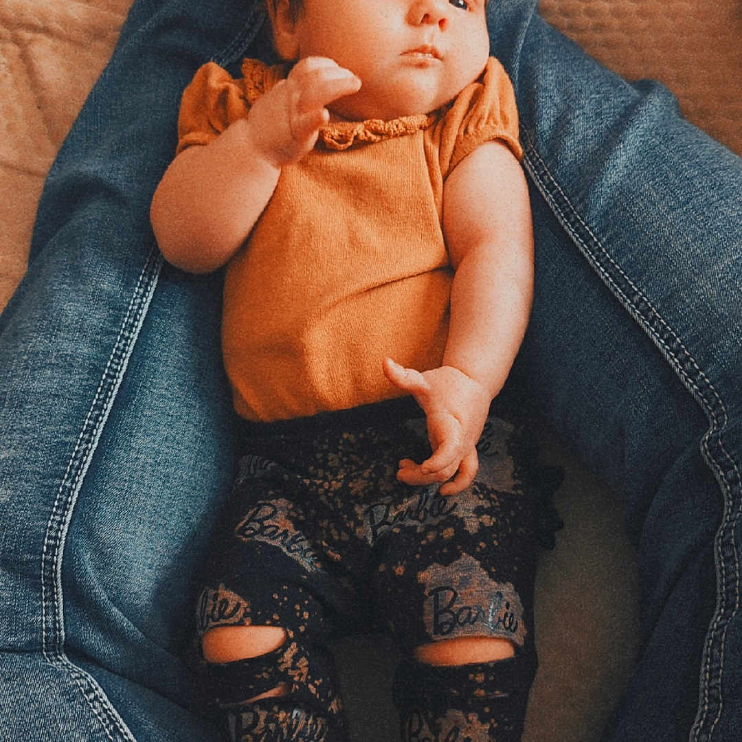 Copelynn joined the competition — help win amazing prizes! baby, barefoot, blanket, casual, child, cute, denim, hair, indoor, infant, jeans, leggings, legs, orange_top, patterned_clothing, person, portrait, relaxed, resting, skin