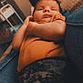 Copelynn is registered to the contest to win money with this photo: baby, infant, child, person, face, clothing, jeans, orange_shirt, patterned_pants, indoor, fan, furniture, couch, relaxed, portrait, home, casual, comfort, closeup, warm_lighting