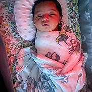 Nova is registered to the contest to win money with this photo: baby, blanket, sleeping, infant, pillow, floral_pattern, cozy, swaddled, cartoon_characters, face, resting, indoors, soft_lighting, cute, child, person, bed, comfort, toddler, peaceful