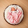 newborn, baby, sleeping, blanket, pink, white_hat, wicker_basket, fluffy, wooden_floor, cozy, infant, peaceful, indoors, soft_texture, child, wrapped, resting, cute, warm, portrait