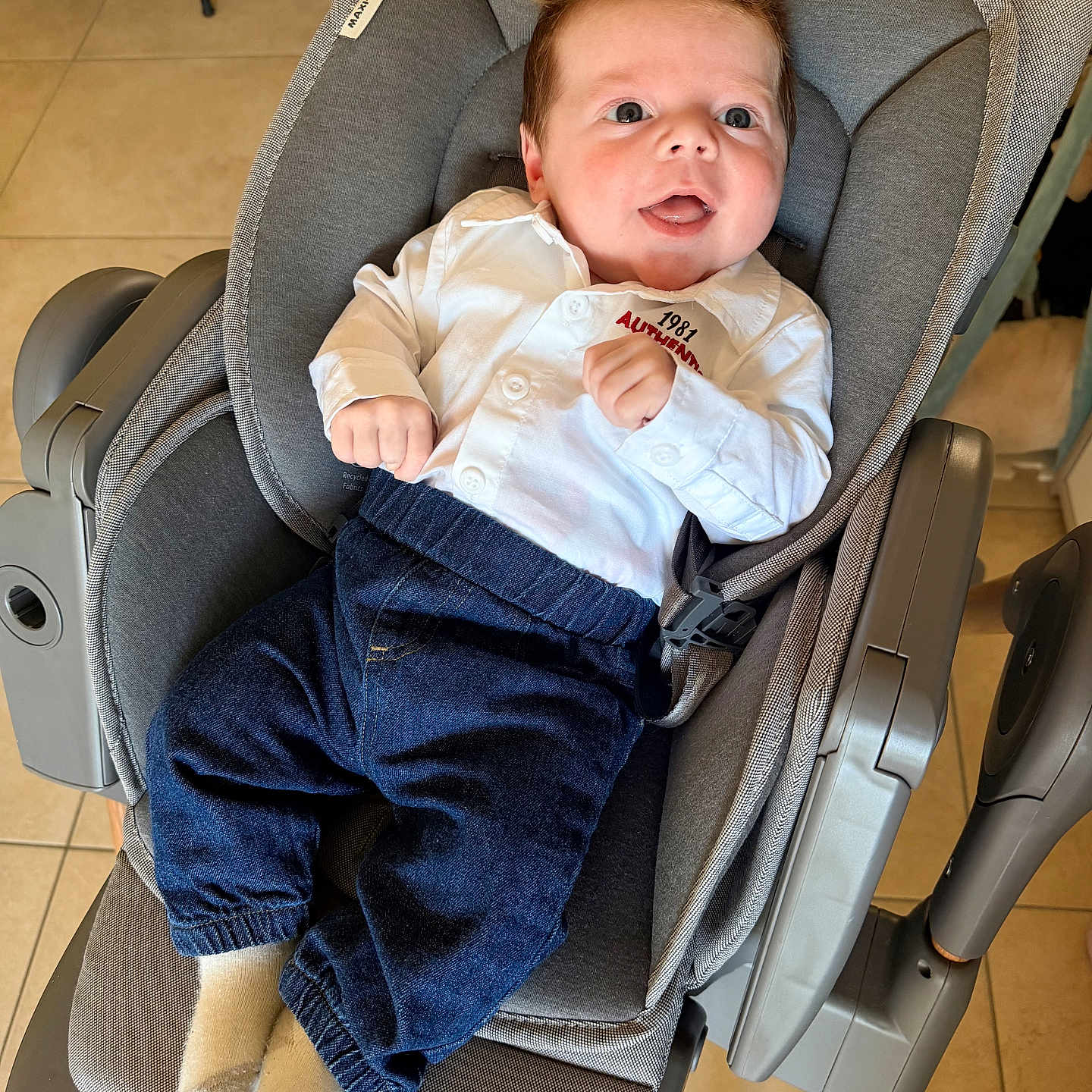 Lyam a rejoint le concours — aidez-le/la à gagner de superbes lots ! baby, baby_rocker, blue_pants, child, cozy, cute, furniture, gray_fabric, happy, home, indoor, infant, person, portrait, seat, smiling, socks, tile_floor, white_shirt, young_child