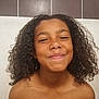 Ylann a rejoint le concours — aidez-le/la à gagner de superbes lots ! casual, child, childhood, curly_hair, cute, expression, face, freckles, happy, head, indoor, joyful, natural_light, person, portrait, shoulders, skin, smile, tiled_wall, young