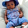 baby, child, infant, blue_hat, romper, cushion, seat, indoor, portrait, face, hands, legs, clothing, cute, looking_at_camera, natural_light, comfortable, soft_texture, relaxed, babywearing