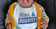 Royal Davis is registered to the contest to win money with this photo: baby, child, smiling, happy, blue_eyes, yellow_jacket, bib, clothing, baby_seat, black_cushion, cute, infant, portrait, indoors, person, hands, open_mouth, casual_wear, joyful, young