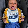 baby, child, smiling, happy, blue_eyes, yellow_jacket, bib, clothing, baby_seat, black_cushion, cute, infant, portrait, indoors, person, hands, open_mouth, casual_wear, joyful, young