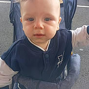 Memphis participe au concours pour gagner de l'argent avec cette photo : child, toddler, stroller, blue_eyes, jacket, pants, outdoor, parking_lot, car, curious, baby, canopy, reaching_out, clothing, person, portrait, infant, young_child, daylight, expression