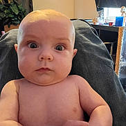 Emerson joined the competition — help win amazing prizes! baby, infant, child, portrait, wide_eyes, surprised_expression, bare_torso, chubby_cheeks, hands_clasped, close_up, indoor, living_room, plant, window, curtain, table, toy, skin, face, person