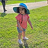 toddler, child, grass, outdoor, sunhat, pink_shirt, shorts, zebra_print, shoes, shadow, daylight, person, curly_hair, playground, blurred_background, adult, greenery, park, casual_clothing, summer