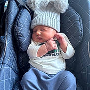 Leon is registered to the contest to win money with this photo: baby, sleeping, car_seat, knit_hat, pom_poms, blue_pants, white_shirt, infant, child, cute, cozy, soft_fabric, padded, indoor, peaceful, hands, face, headwear, child_boy, resting