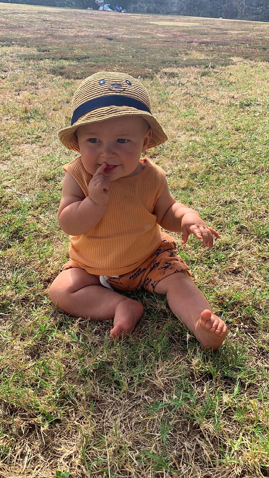 Lissandro a rejoint le concours — aidez-le/la à gagner de superbes lots ! baby, baby_toddler_clothing, baseball_cap, cap, child, foot, fun, grass, grass_family, grassland, hand, hat, headwear, human_leg, landscape, people_in_nature, person, plant, sitting, sleeve