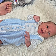 Oliver-John is registered to the contest to win money with this photo: baby, baby_clothes, blue_outfit, closeup, curious_expression, cute_clothing, hand, human, indoor, infant, lying_down, newborn, person, portrait, skin, small_hands, soft_texture, tattoo, white_rug, wide_eyes