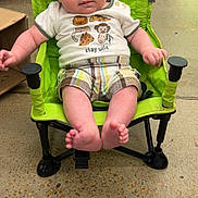 Gideon is registered to the contest to win money with this photo: animal_shirt, baby, background, casual_clothing, child, concrete_floor, curious_expression, face, floor, footwear, green_chair, hands, indoor, infant, legs, person_walking, plaid_shorts, portable_chair, seated, young_child