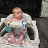 baby, walker, infant, floor, toy, rainbow_pattern, colorful, sitting, curious, indoor, carpet, furniture, black_chair, child, young, person, footwear_absent, head, face, home