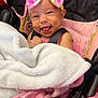 baby, child, car_seat, blanket, pink_bow, smile, happy, infant, clothing, seatbelt, fabric, cute, headband, person, toddler, indoors, soft_texture, wrapped, closeup, face