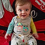 Kenzo a rejoint le concours — aidez-le/la à gagner de superbes lots ! baby, child, smiling, happy, blue_eyes, sitting, clothing, colorful, blanket, indoor, cute, infant, portrait, playful, cartoon_print, young_child, face, person, expression, joyful