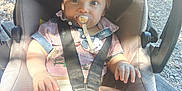 Kenzo a rejoint le concours — aidez-le/la à gagner de superbes lots ! baby, pacifier, car_seat, outdoor, sunlight, shadow, child, toddler, seatbelt, clothing, person, skin, legs, hand, face, hair, nature, wood, ground, daylight
