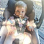 baby, pacifier, car_seat, outdoor, sunlight, shadow, child, toddler, seatbelt, clothing, person, skin, legs, hand, face, hair, nature, wood, ground, daylight