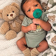 Kayceon is registered to the contest to win money with this photo: baby, blanket, child, cozy, cuddly, dark_hair, indoor, infant, lying_down, nursery, onesie, pacifier, photography, portrait, smiling, socks, soft_texture, teddy_bear, toy, wide_eyed