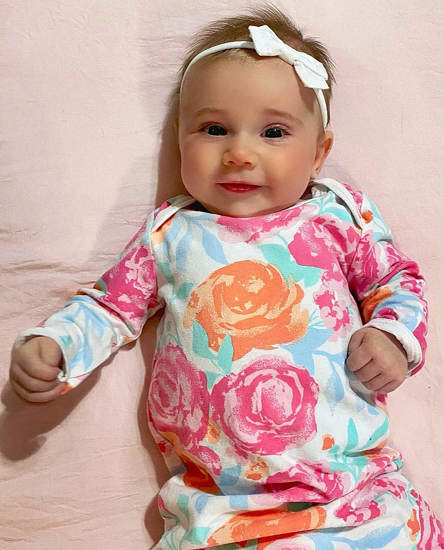Maisie is registered to the contest to win money with this photo: baby, baby_toddler_clothing, cheek, clothing, collar, dress, eyelash, face, hand, happy, head, headwear, neck, nose, outerwear, person, pink, skin, sleeve, smile