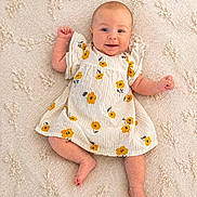 Kiara participe au concours pour gagner de l'argent avec cette photo : baby, infant, smiling, dress, yellow_flowers, blanket, texture, cute, happy, lying_down, skin, foot, hand, cheerful, child, portrait, indoors, person, newborn, clothing