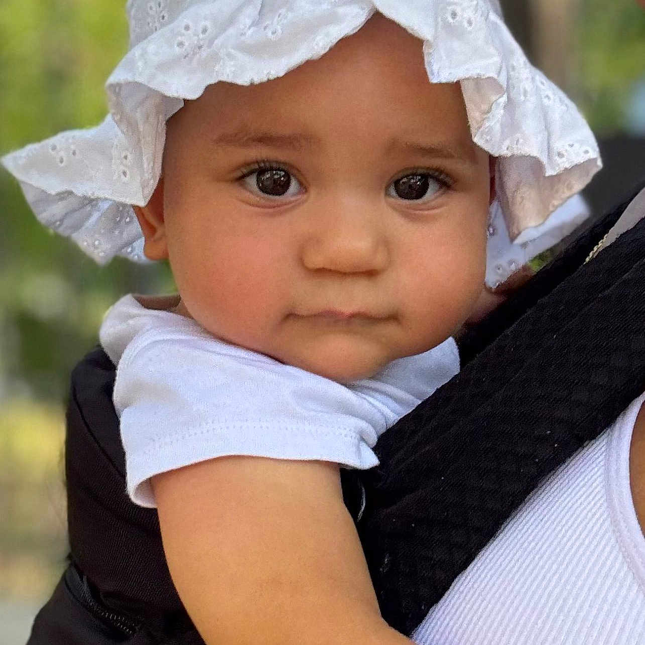Eyvi a rejoint le concours — aidez-le/la à gagner de superbes lots ! baby, carrier, child, closeup, cute, expression, eyelashes, face, hat, headwear, holding, infant, outdoor, person, portrait, shoulder, skin, summer, sunlight, white_clothing