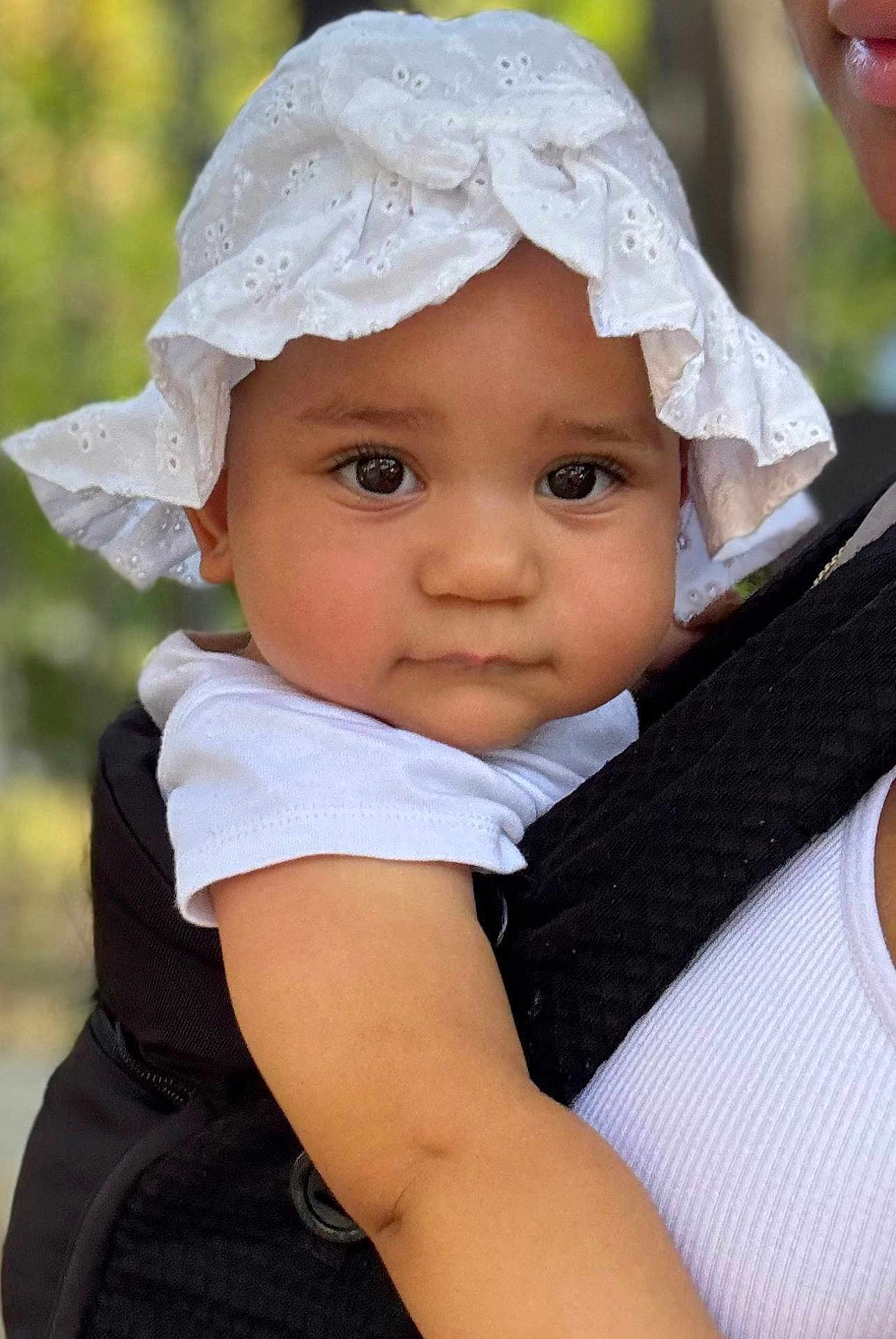 Eyvi a rejoint le concours — aidez-le/la à gagner de superbes lots ! baby, child, face, hat, white_clothing, outdoor, closeup, portrait, carrier, person, cute, infant, skin, eyelashes, shoulder, summer, sunlight, expression, headwear, holding