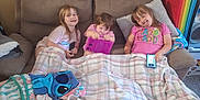 Ava joined the competition — help win amazing prizes! blanket, casual, child, children, couch, cozy, furniture, happy, home, indoor, living_room, plaid, playing, relaxed, seated, smartphone, smiling, tablet, technology, three_people