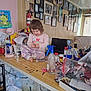 Violet is registered to the contest to win money with this photo: bottle, chair, child, clutter, coins, countertop, fire_extinguisher, foot, indoor, lamp, laptop, pajamas, papers, pen_holder, photographs, plastic_bag, scissors, table, toddler, wall_art
