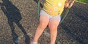 Violet is registered to the contest to win money with this photo: child, toddler, swing, playground, yellow_shirt, shorts, sandals, grass, sunlight, shadow, outdoor, summer, happy, play, fun, daylight, casual_clothing, person, nature, recreation