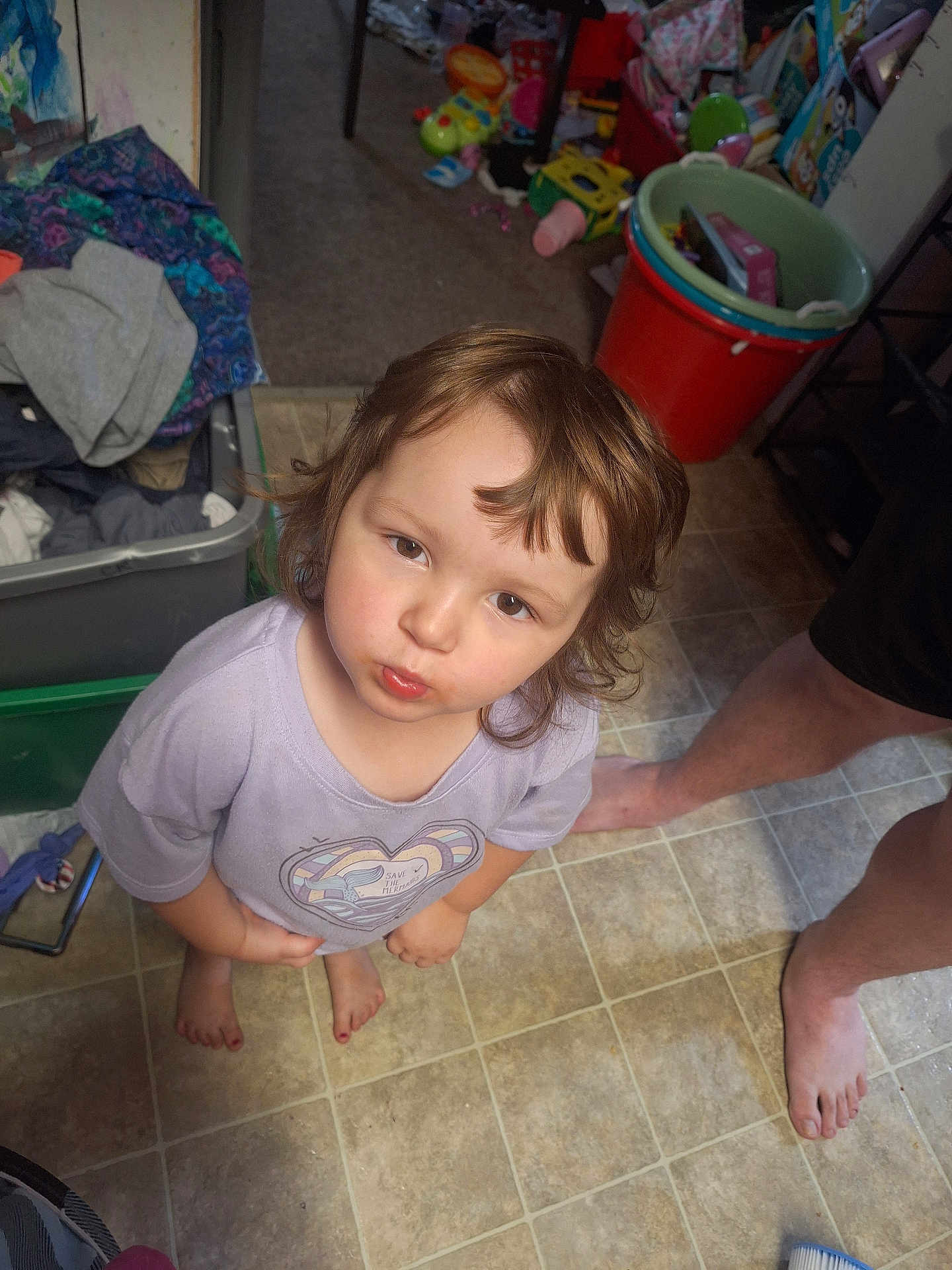 Violet joined the competition — help win amazing prizes! adult, barefoot, casual, child, clutter, curious, expression, floor, hair, home, indoor, legs, looking_up, person, room, shirt, standing, tile_floor, toddler, toy