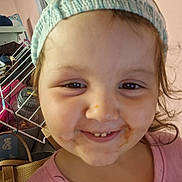 Violet is registered to the contest to win money with this photo: child, toddler, face, smile, hat, knitted_hat, pink_shirt, indoors, messy_face, food_stains, brown_hair, eyes, person, closeup, cute, happy, expression, headwear, baby, portrait