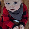 baby, child, plush_toy, reindeer, red_pajamas, black_pajamas, blue_eyes, wooden_floor, indoors, hands, face, clothing, cute, infant, young_child, sitting, toy, expression, floor, looking_up