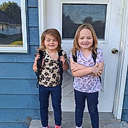 Twins joined the competition — help win amazing prizes! children, backpacks, door, house, concrete, step, blue_wall, smiling, standing, casual_clothing, patterned_shirts, shoes, outdoor, person, young, two_people, happy, childhood, daylight, siblings