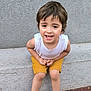 brown_hair, casual_clothing, child, concrete, cute, daylight, feet, happy, knees, outdoor, person, playful, portrait, sandals, shorts, sitting, skin, smiling, white_shirt, young_child