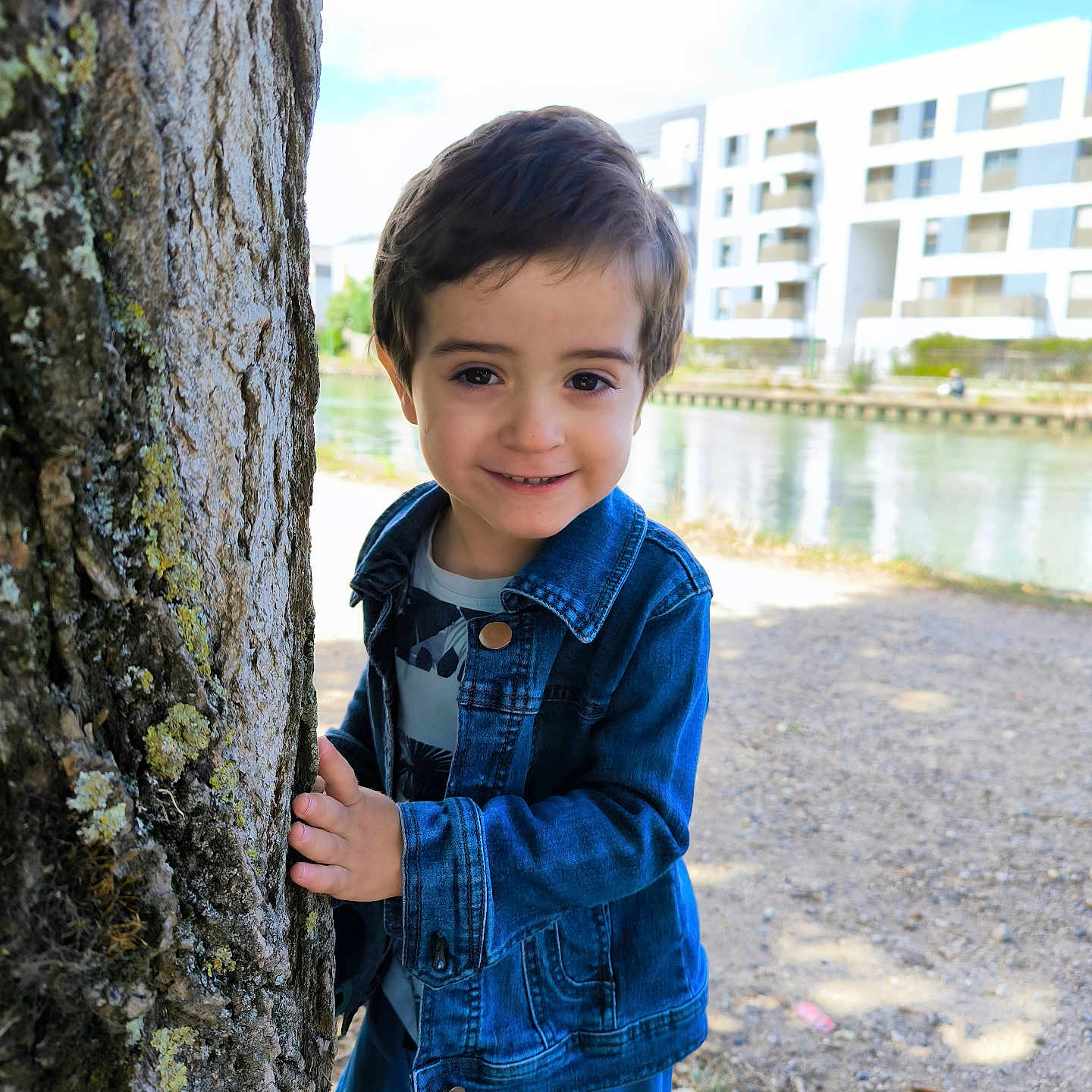 Enzo Fernandes a rejoint le concours — aidez-le/la à gagner de superbes lots ! boy, building, canal, casual_clothing, child, daylight, denim_jacket, happy, nature, outdoor, park, person, playful, portrait, sky, smiling, tree, urban, water, young