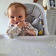 Lyse participe au concours pour gagner de l'argent avec cette photo : baby, high_chair, food, messy, smiling, face, hand, clothing, cushion, home, table, portrait, child, cute, indoor, person, feeding, happy, hair, seat