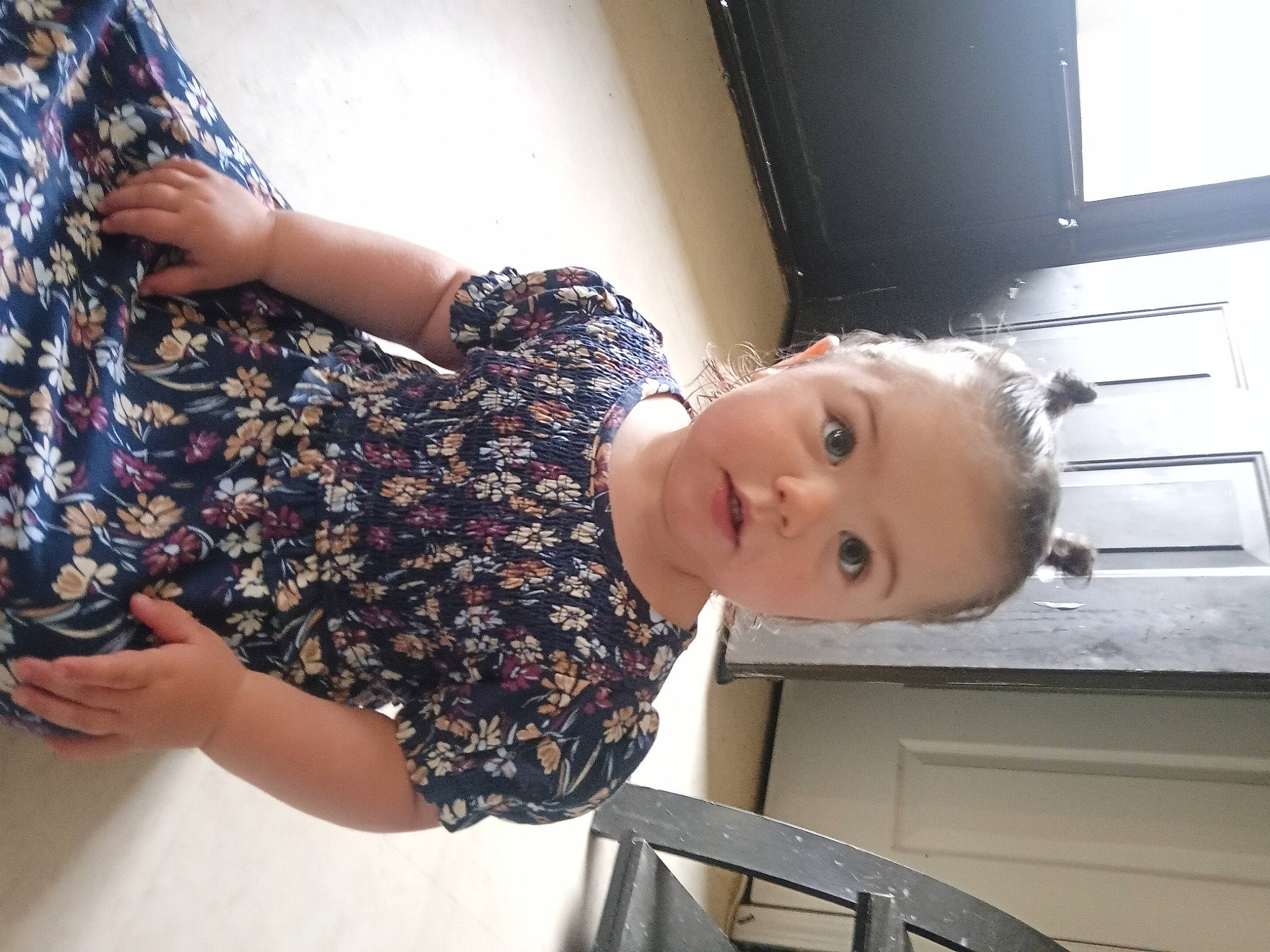 Ava-madison is registered to the contest to win money with this photo: baby, child, dress, elbow, fashion_design, gesture, happy, human_leg, joint, pattern, person, sleeve, standing, thigh, toddler, tree, trunk, waist, window, wood