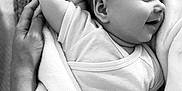 Noé participe au concours pour gagner de l'argent avec cette photo : baby, infant, sleeping, blanket, hand, black_and_white, soft_texture, peaceful, close_up, cuddle, newborn, smile, person, skin, comfort, rest, portrait, gentle, love, tenderness