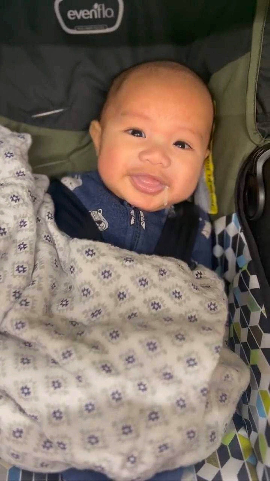 Kian is registered to the contest to win money with this photo: baby, baby_products, baby_safety, baby_toddler_clothing, car_seat, cheek, child, collar, comfort, facial_expression, happy, iris, linens, outerwear, pattern, person, sleeve, smile, toddler