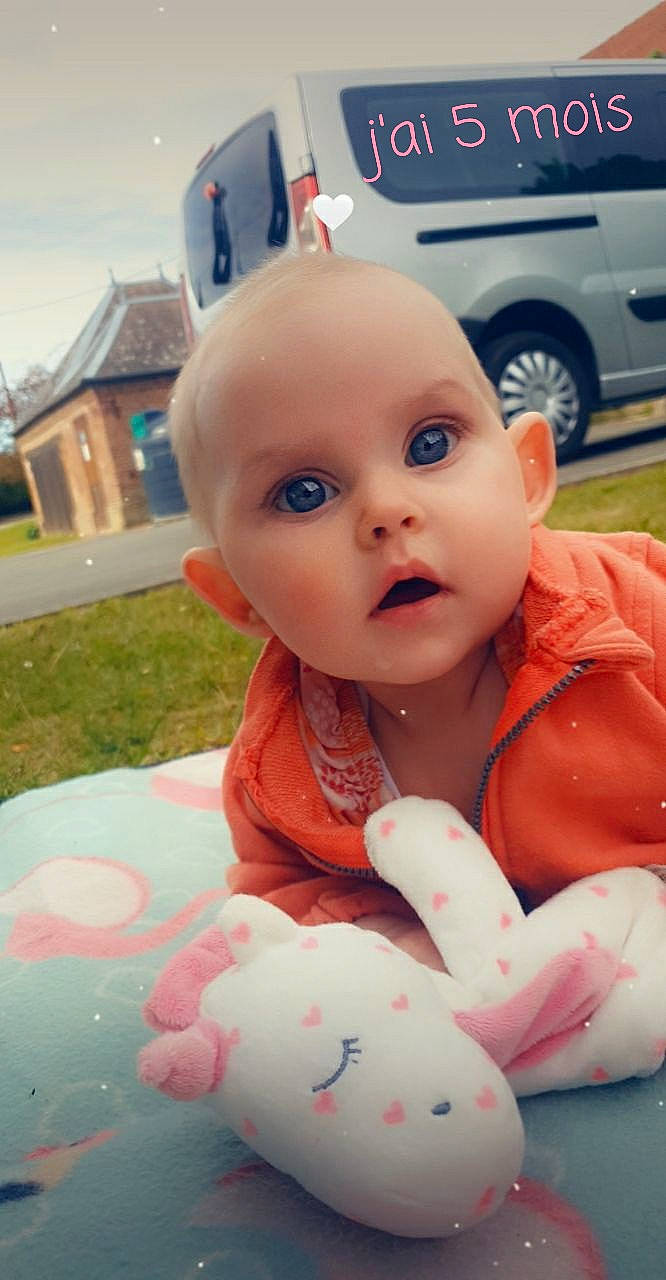 Bella a rejoint le concours — aidez-le/la à gagner de superbes lots ! automotive_exterior, automotive_tire, baby, baby_toddler_clothing, child, family_car, fun, grass, happy, motor_vehicle, nose, person, pink, recreation, sitting, sky, surprise, tire, toddler, vehicle_door