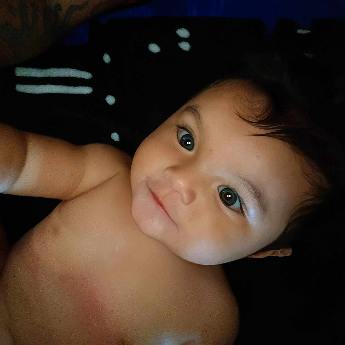 Clyde is registered to the contest to win money with this photo: baby, child, infant, portrait, face, eyes, smiling, happy, lying_down, indoor, blanket, dark_background, close_up, bare_shoulders, skin, brown_hair, looking_at_camera, cozy, photography, adorable