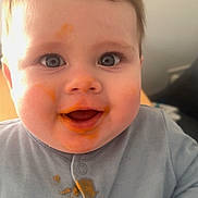 George joined the competition — help win amazing prizes! baby, child, messy, food, orange_food, smile, happy, face, blue_clothing, portrait, closeup, infant, cute, eyes, messy_face, eating, indoor, casual, childhood, fun
