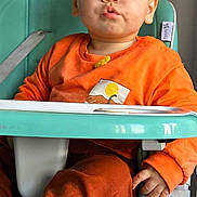 Vladian participe au concours pour gagner de l'argent avec cette photo : toddler, child, high_chair, orange_clothing, blue_eyes, indoor, pout, snack, face, hand, seat, baby, person, cute, furniture, expression, young_child, sitting, casual, portrait